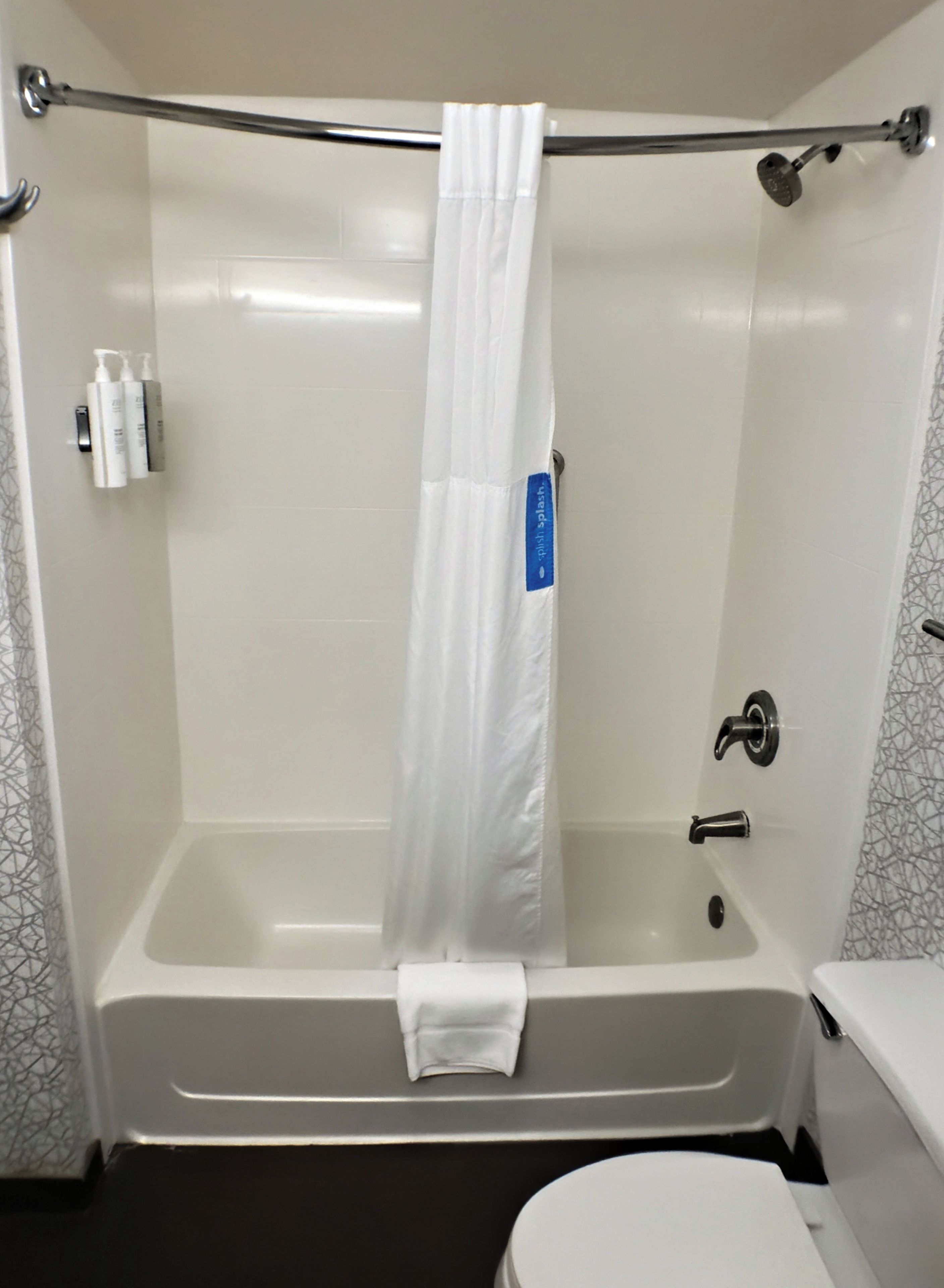 Et badeværelse med badekar, toilet og brusenissemærke.
