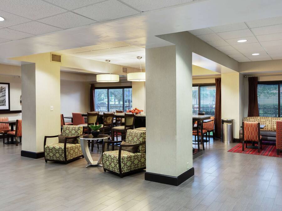 A spacious lobby with multiple seating areas, a reception desk, and large windows providing natural light.