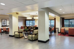 A spacious lobby with multiple seating areas, a reception desk, and large windows providing natural light.