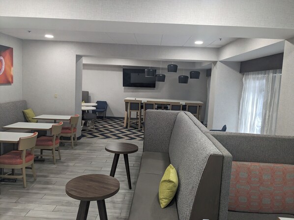A modern lounge area with seating arrangements, a flat-screen TV, and a patterned floor.