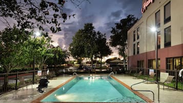 Una piscina al aire libre, sombrillas, sillones reclinables de piscina