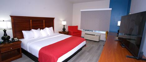 Habitación de hotel con cama, escritorio, televisión, silla, lámpara y calefactor.