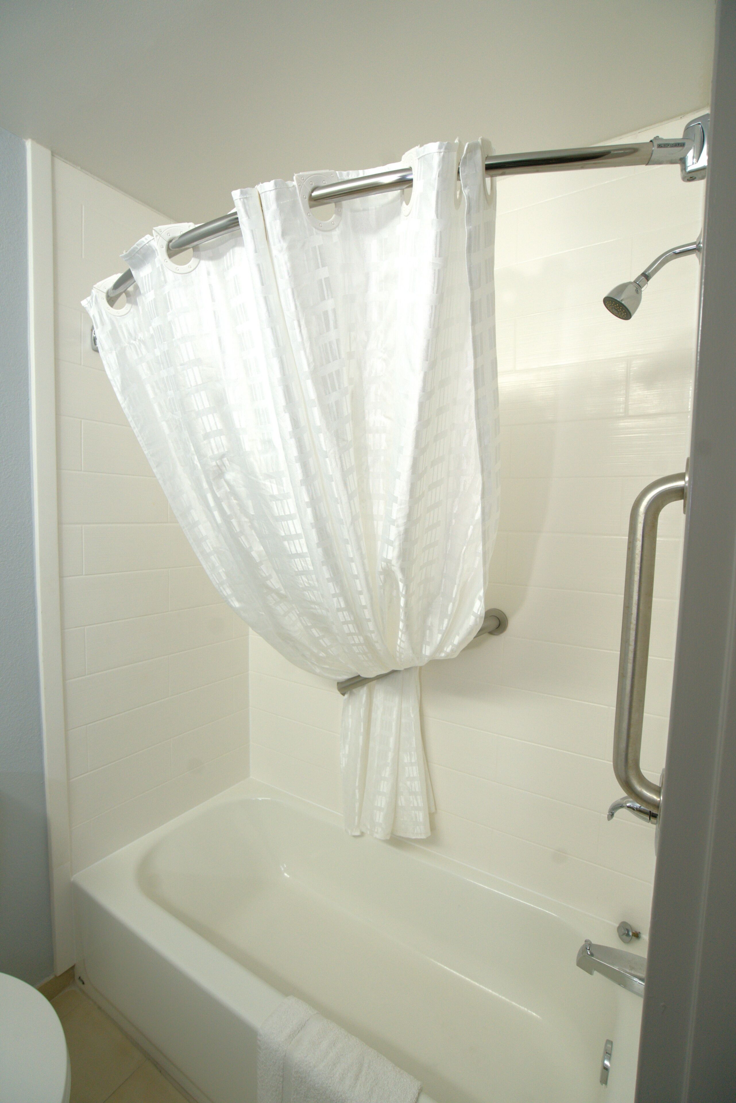 Une salle de bain équipée d’une baignoire, d’un rideau de douche et d’une barre d’appui.