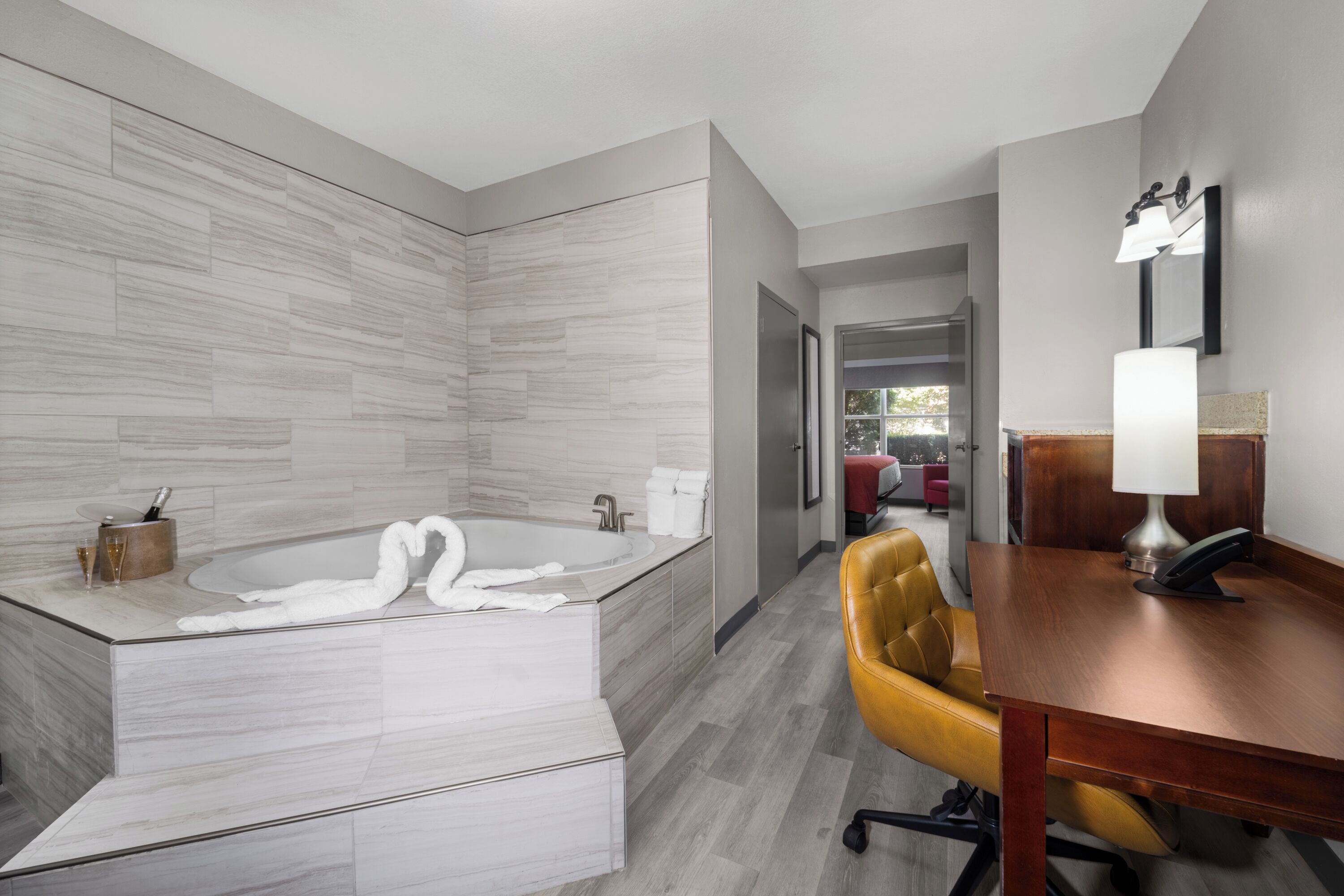 A modern bathroom with a freestanding bathtub, a wooden vanity, and a yellow chair.
