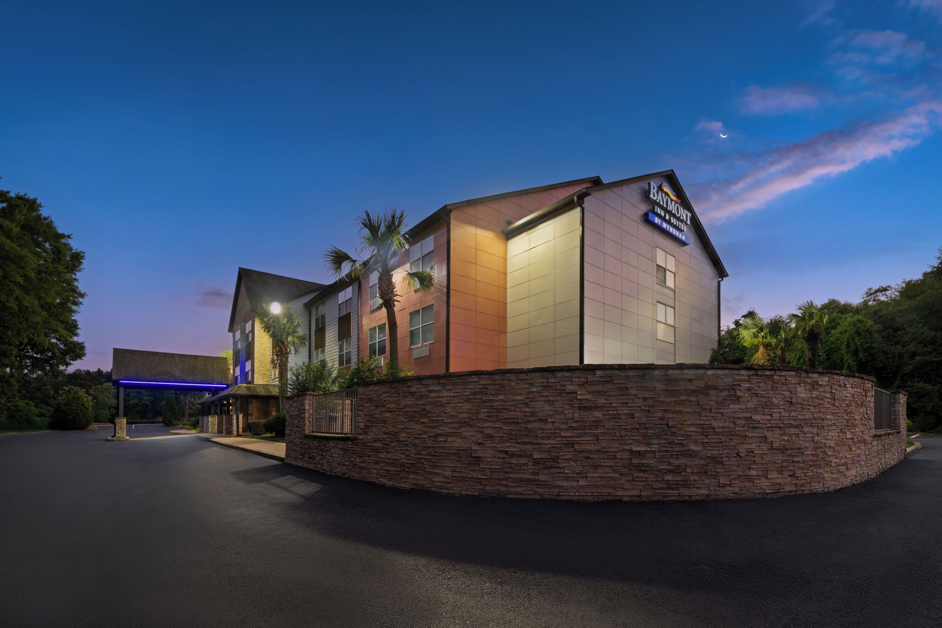 Een hotel met een stenen gevel, een bord met Baymont Inn & Suites en een parkeerplaats.