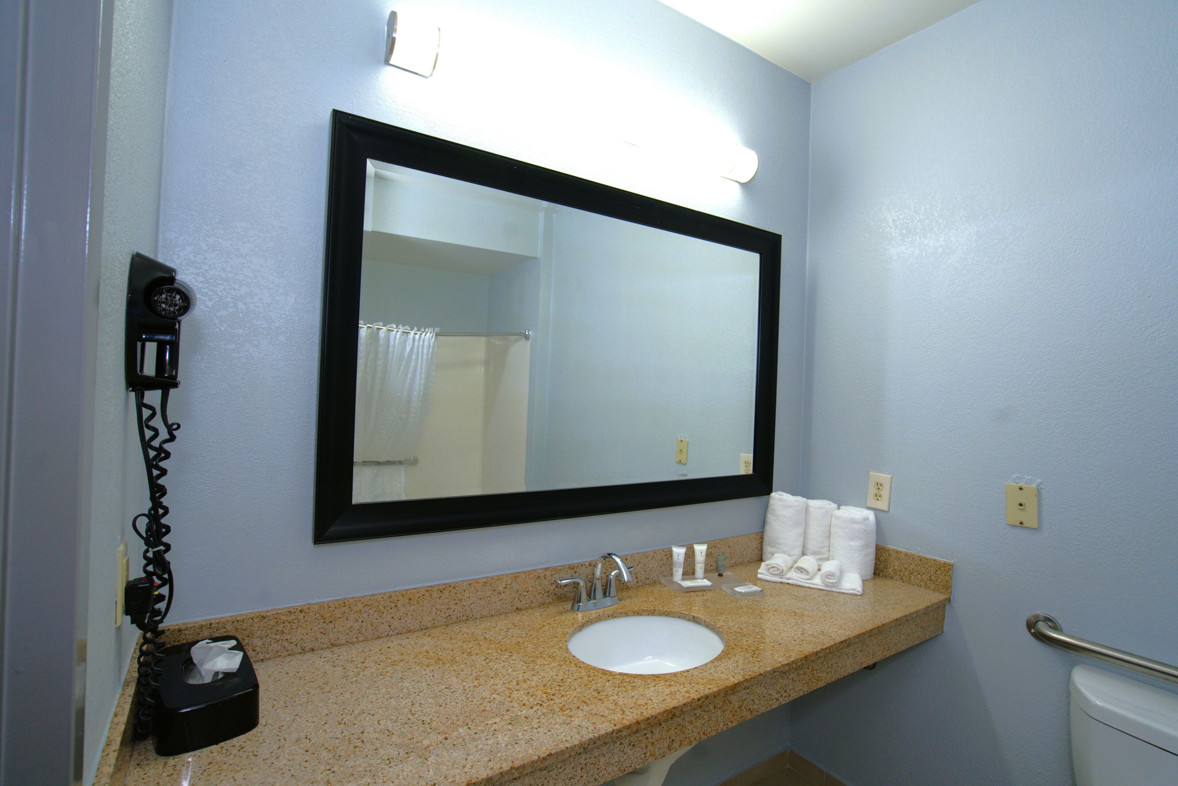 Un baño con lavamanos, espejo, dispensador de toallas y retrete.