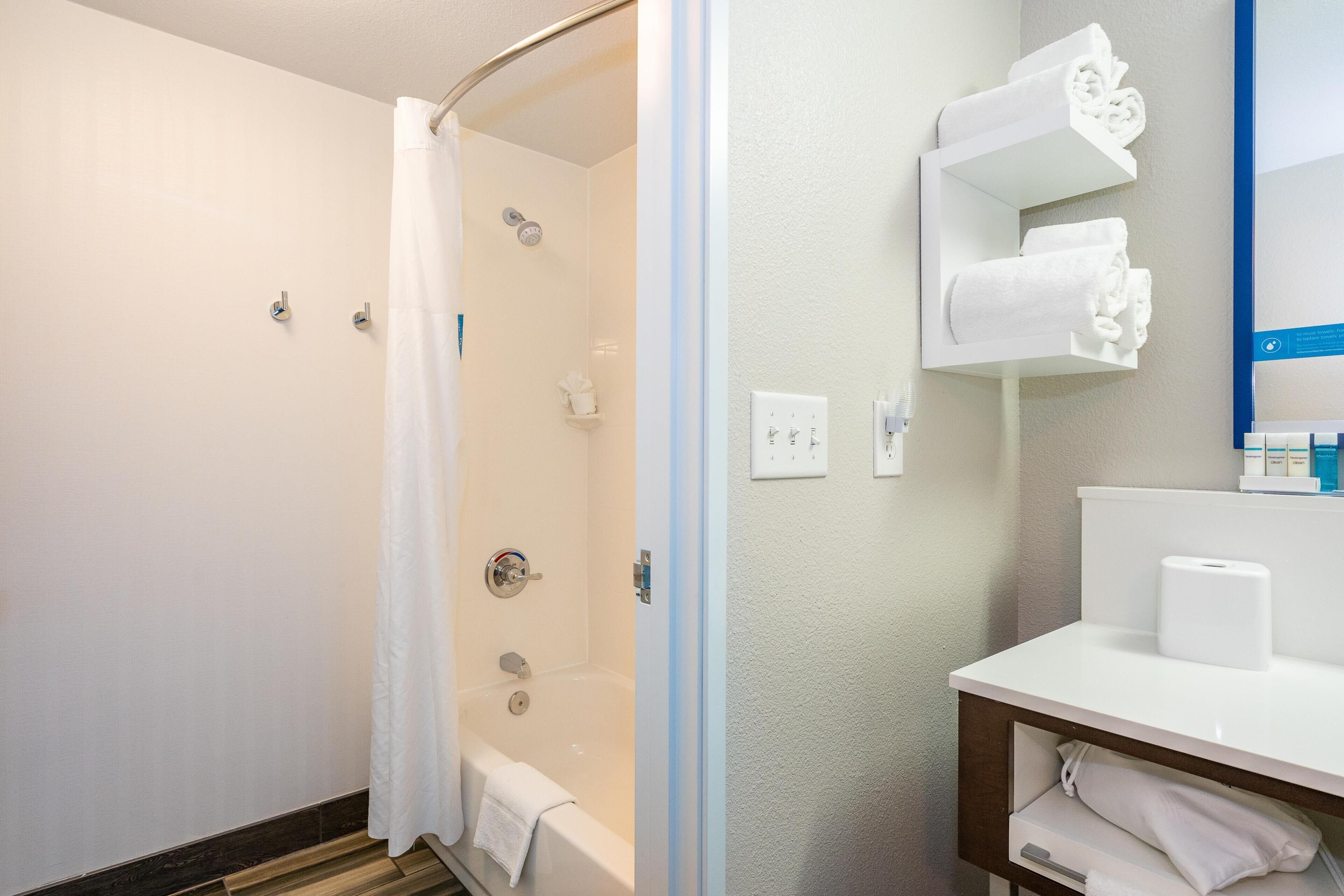 A bathroom with a shower, a toilet, a sink, and a towel rack.
