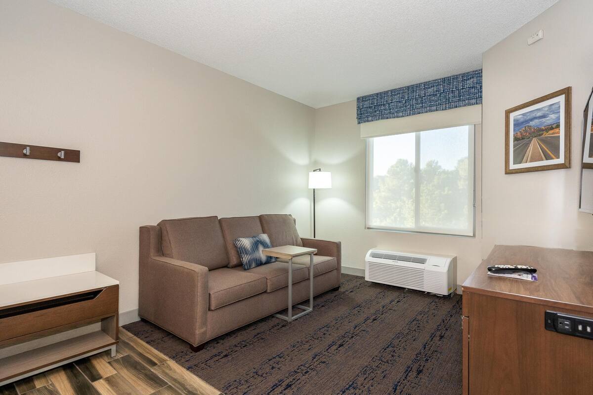 Une chambre d’hôtel avec un canapé, une petite table, un radiateur et une fenêtre donnant sur un beau paysage.