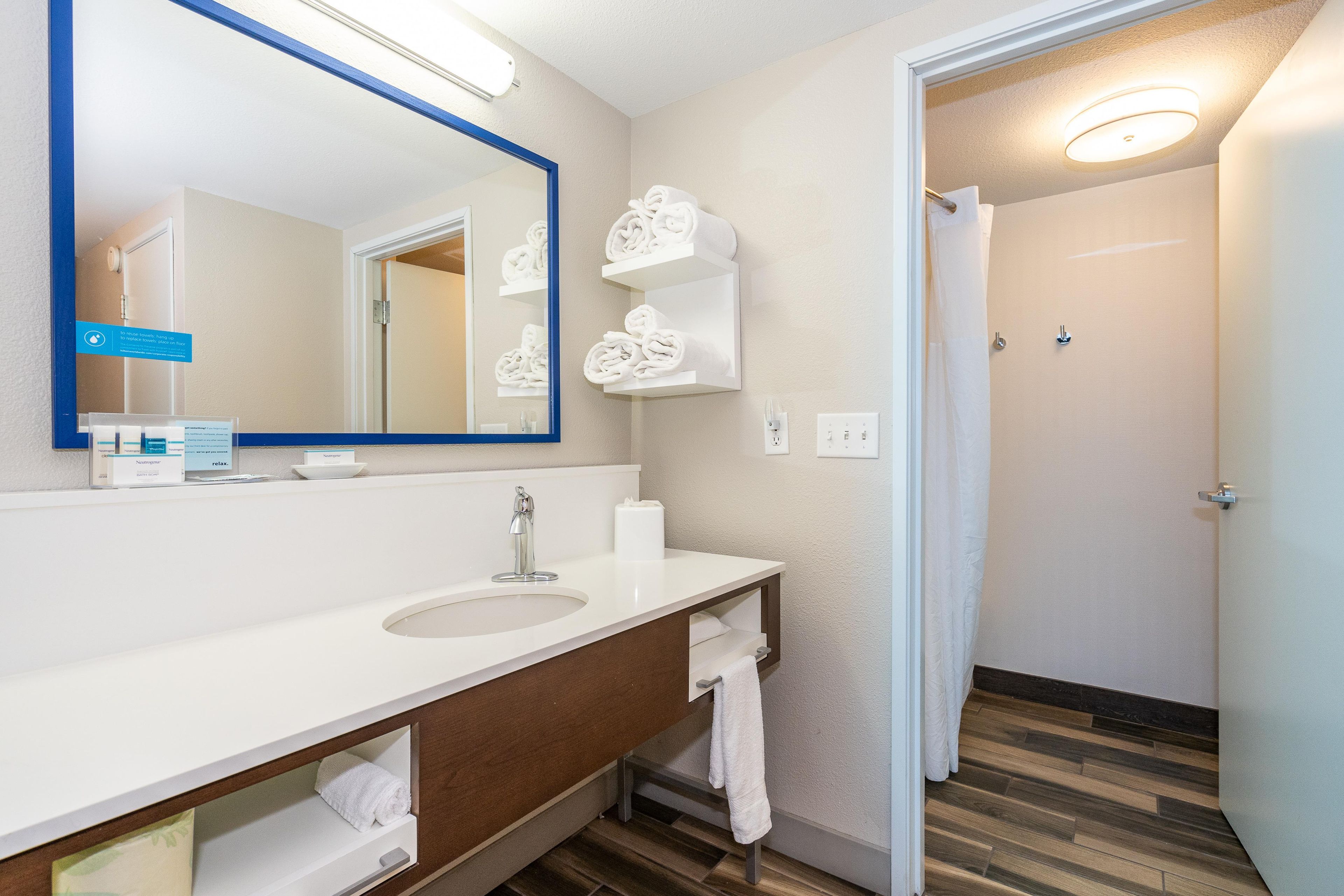 Une salle de bain moderne avec un grand miroir, un lavabo blanc et des porte-serviettes.