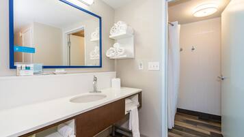 Une salle de bain moderne avec un grand miroir, un lavabo blanc et des porte-serviettes.