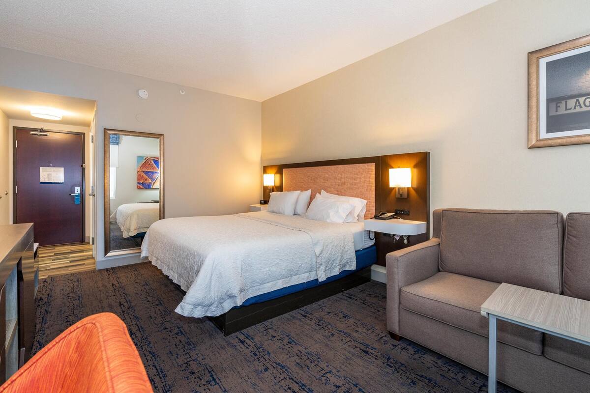Une chambre d’hôtel avec un lit, un canapé, un bureau et un miroir.