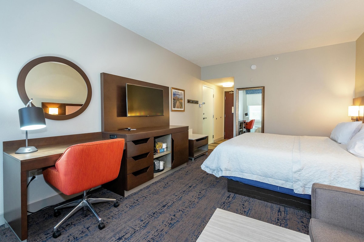 Une chambre d’hôtel équipée d’un lit, d’un bureau, d’une chaise, d’une télévision et d’un miroir.