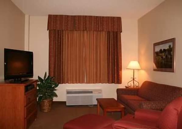 A living room with a television, a sofa, a lamp, and a plant.