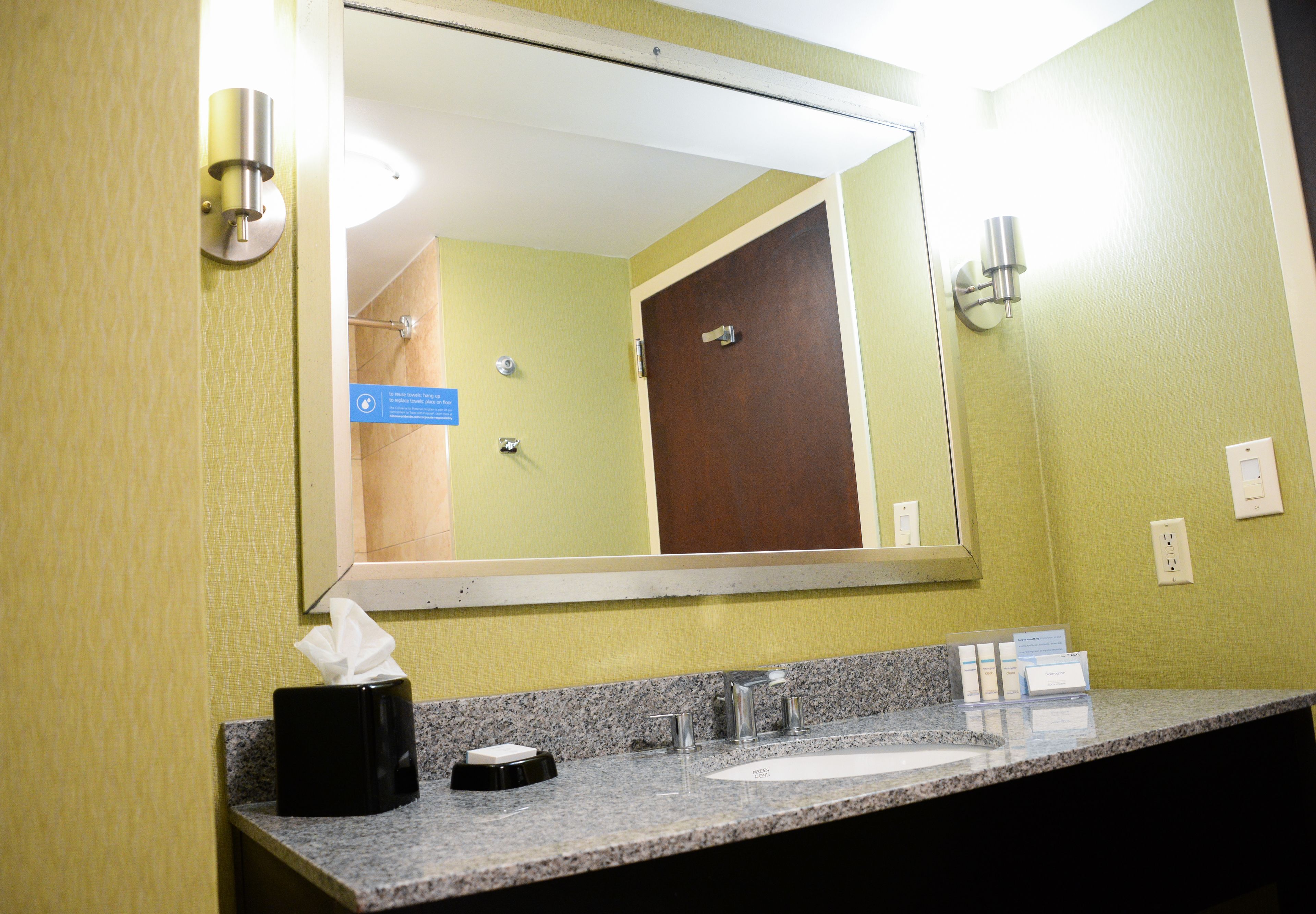 A bathroom with a granite countertop, a sink, a mirror, and a door.