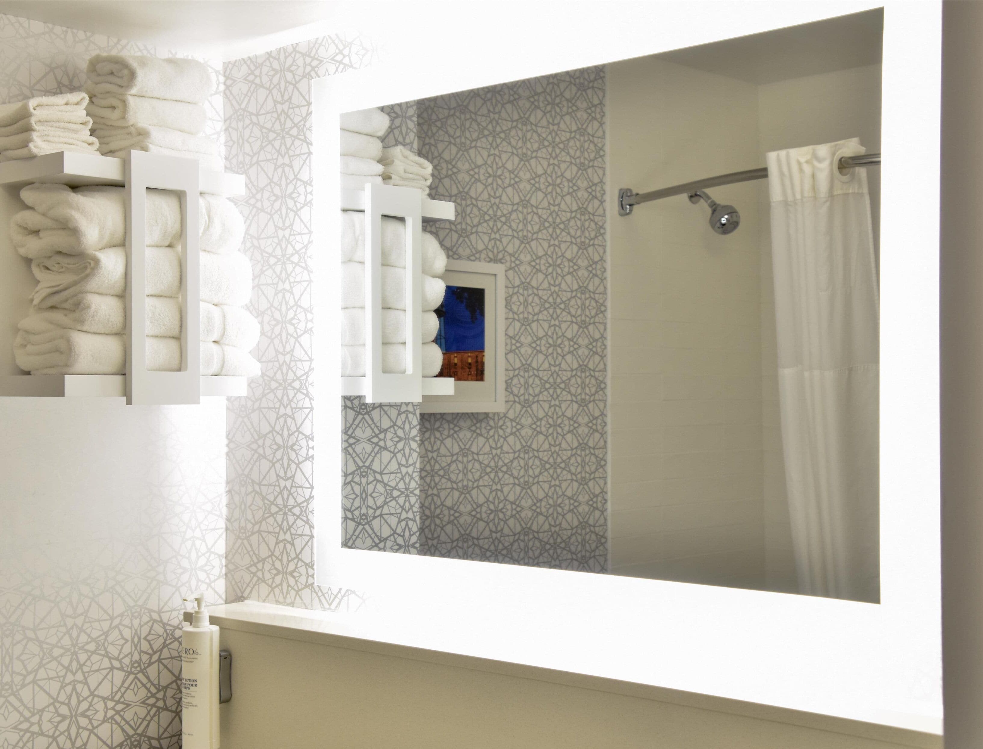 Une salle de bain équipée d’un porte-serviettes, d’un rideau de douche et d’une fenêtre ornée d’un motif géométrique.