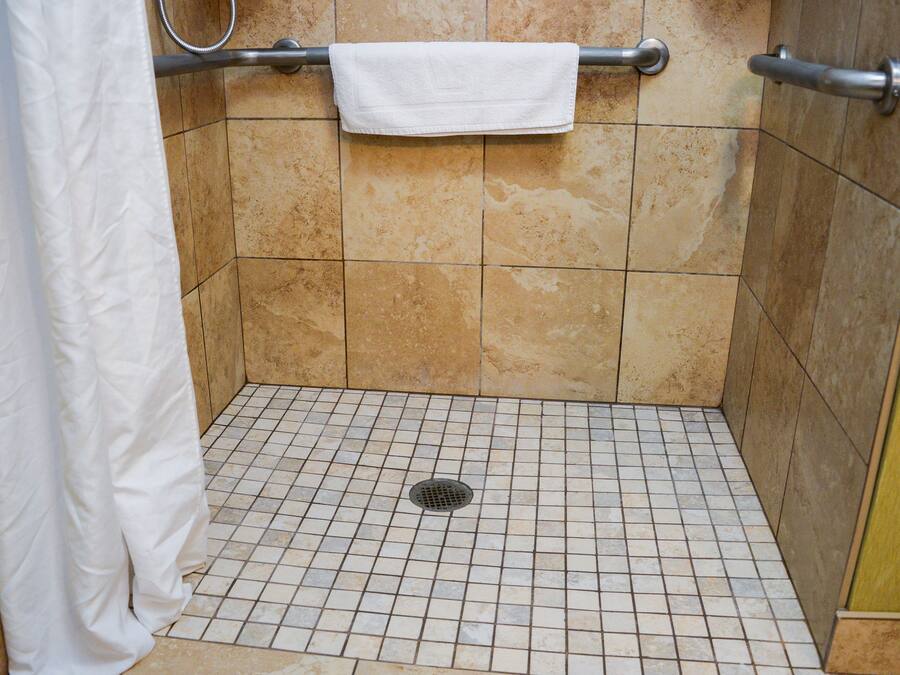 Un área de ducha con piso de azulejos, un desagüe y un perchero para toallas.