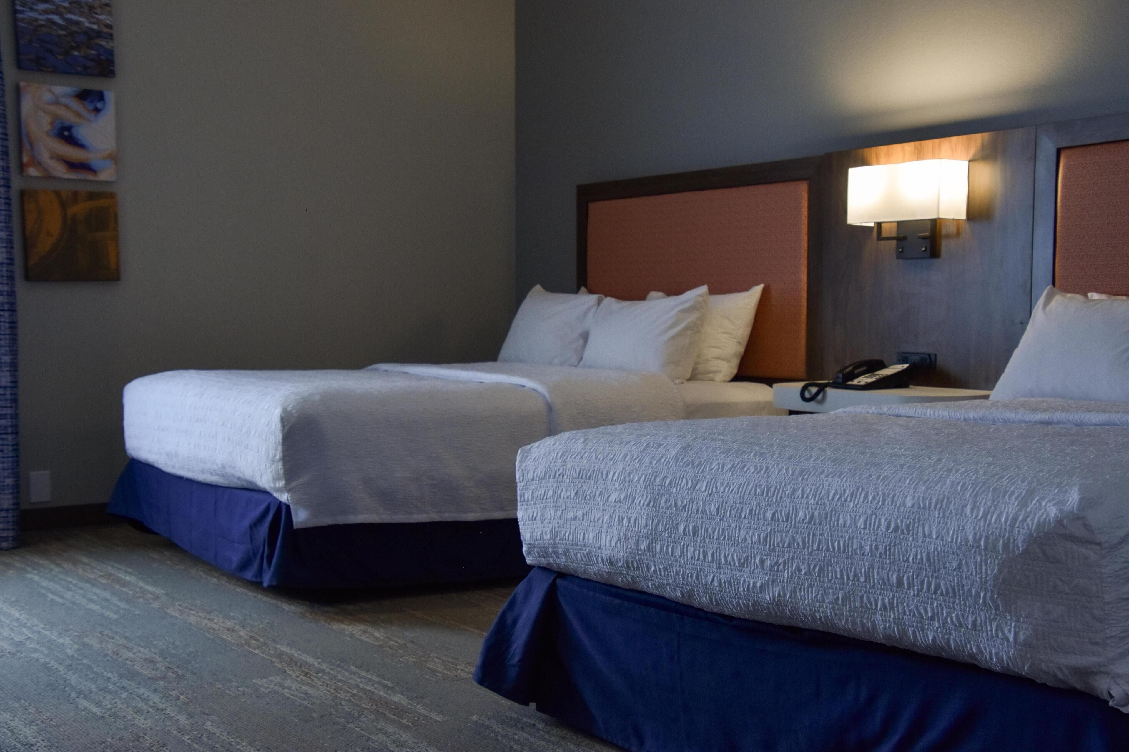 Une chambre d’hôtel avec deux lits, chacun doté d’une tête de lit et d’une lampe de chevet.