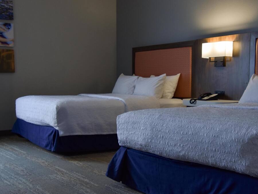 Une chambre d’hôtel avec deux lits, chacun doté d’une tête de lit et d’une lampe de chevet.
