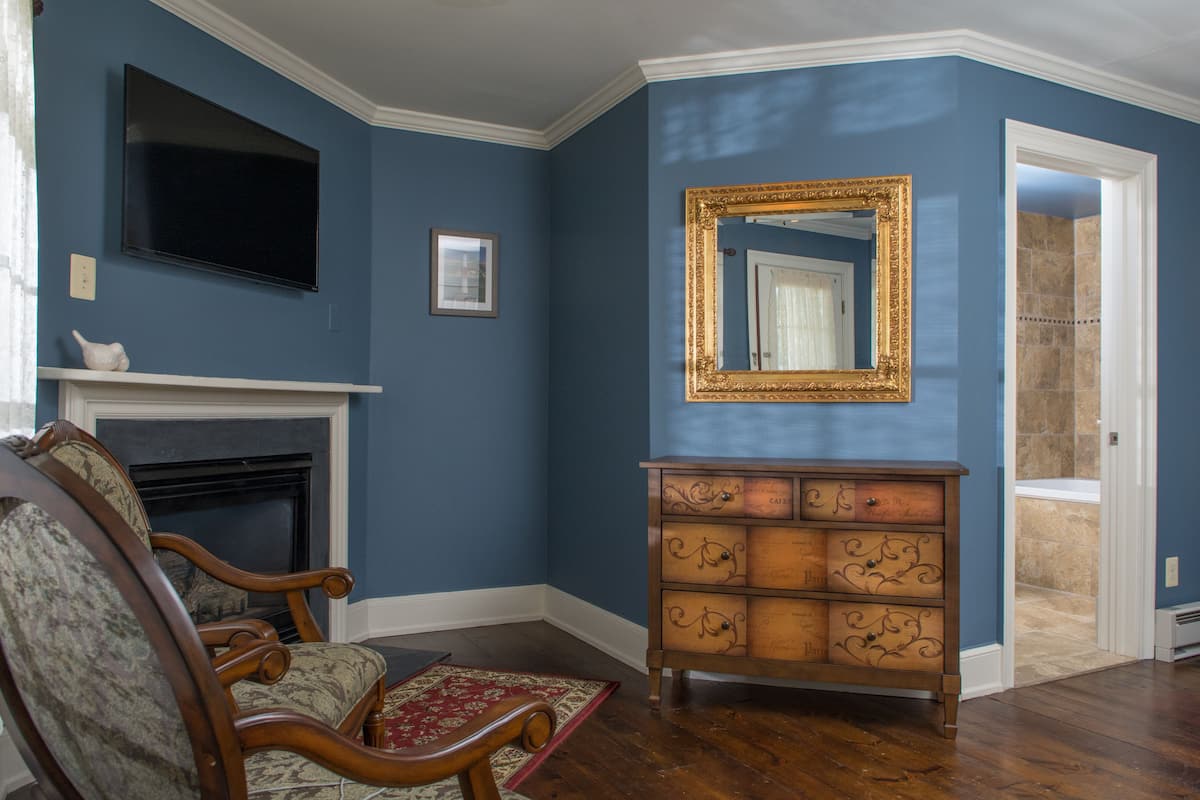 A living room with a fireplace, a television, a mirror, and a wooden dresser.