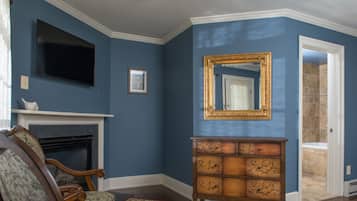 Una sala de estar con chimenea, televisor, espejo y cómoda de madera.