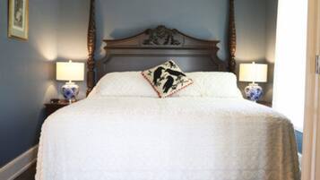 A bedroom with a large bed, two bedside tables with lamps, and a decorative headboard.