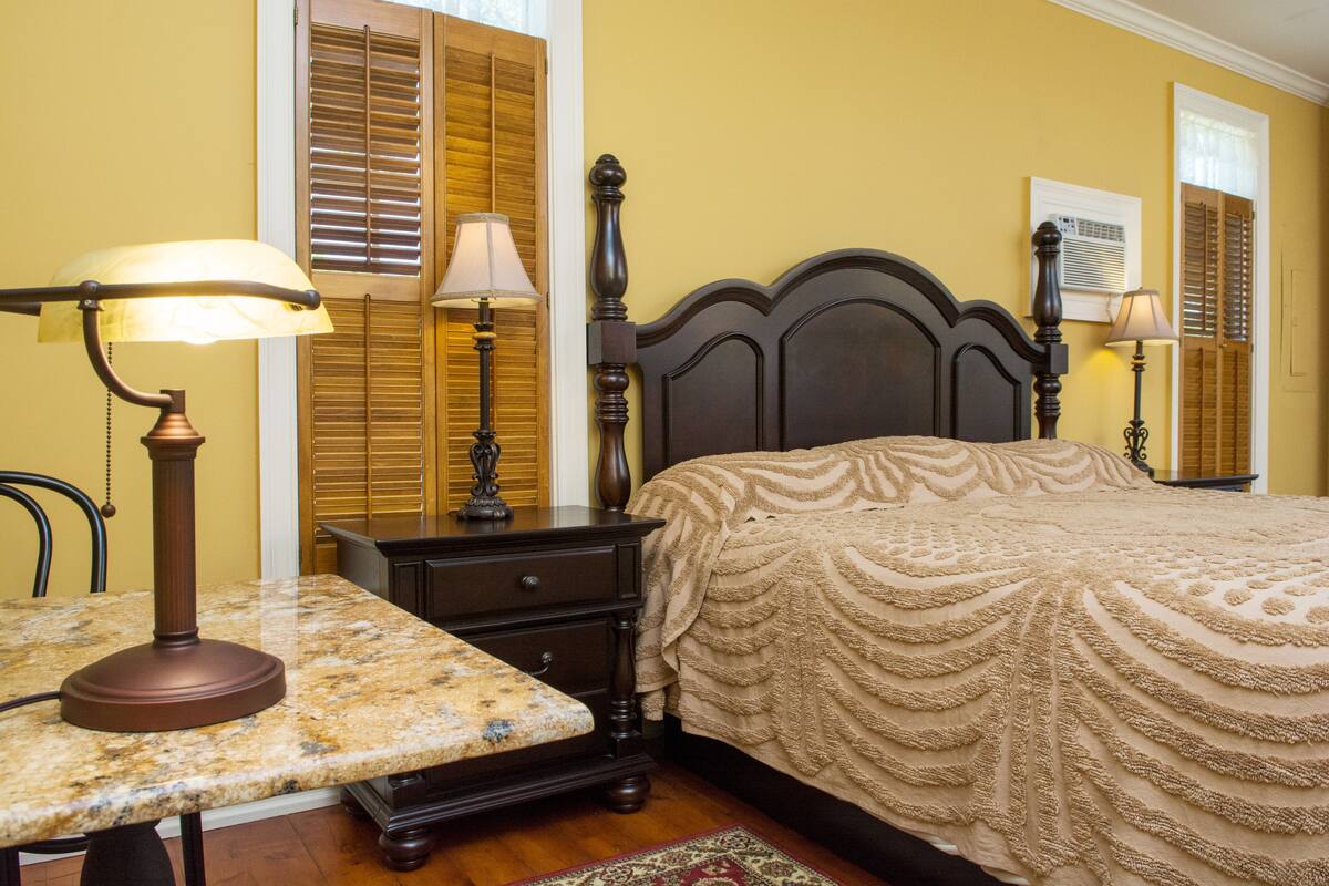 A bedroom with a bed, nightstands, a lamp, and a chair.