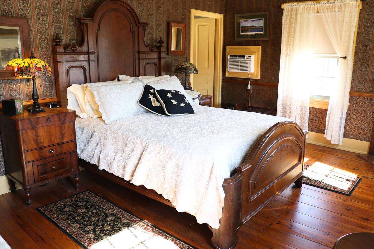 A traditional bedroom with a wooden bed, a nightstand, a dresser, and a patterned rug.