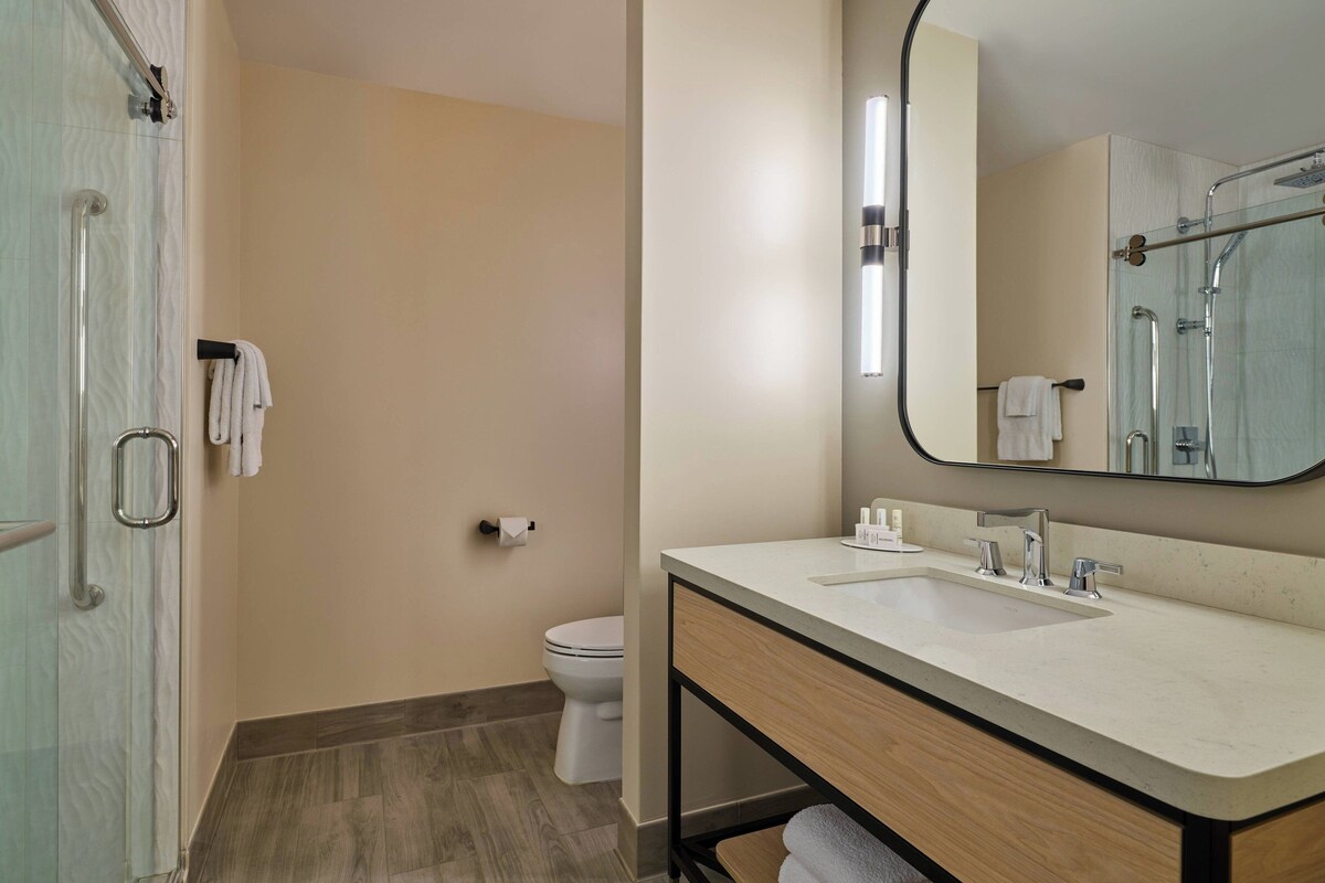 A modern bathroom with a glass shower enclosure, a toilet, and a vanity with a sink and mirror.