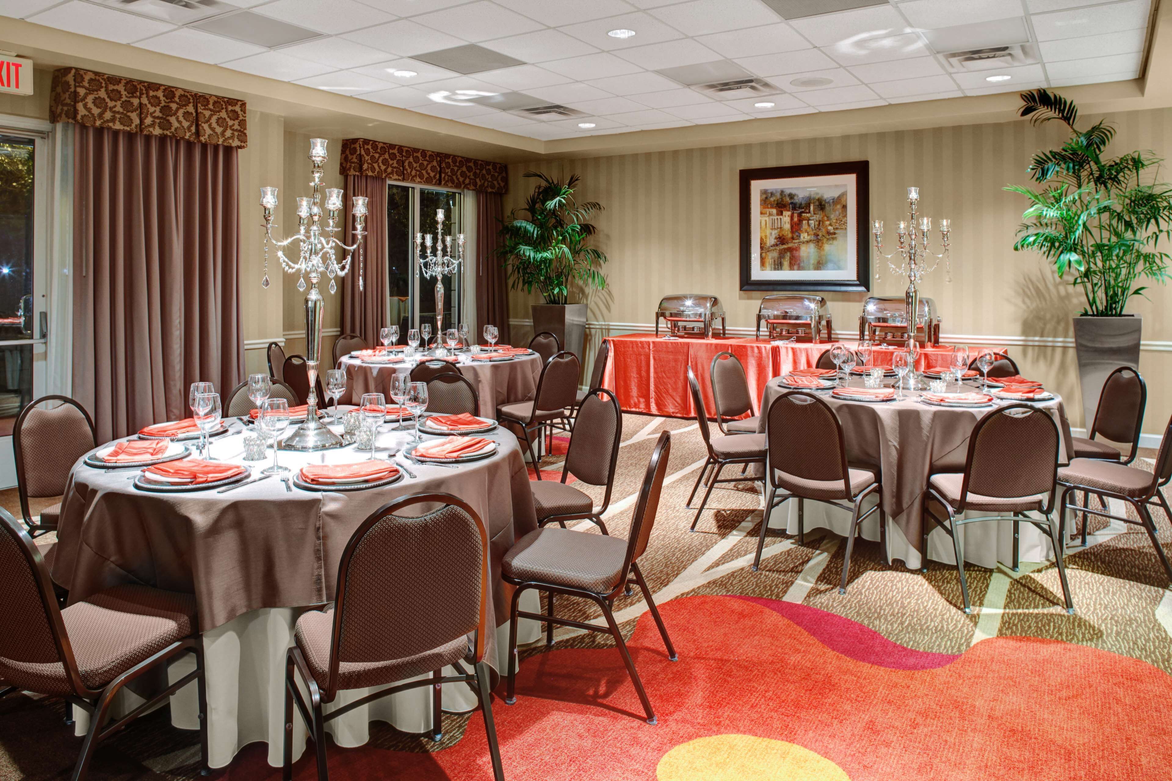 A conference room with round tables, chairs, and a carpeted floor.