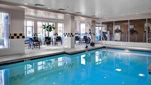 A swimming pool with a tiled edge, a lounge area with chairs, and exercise equipment. - Hilton Garden Inn Atlanta North/Alpharetta (Alpharetta)