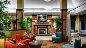 A spacious lobby with a fireplace, comfortable seating, and decorative plants. - Hilton Garden Inn Atlanta North/Alpharetta (Alpharetta)