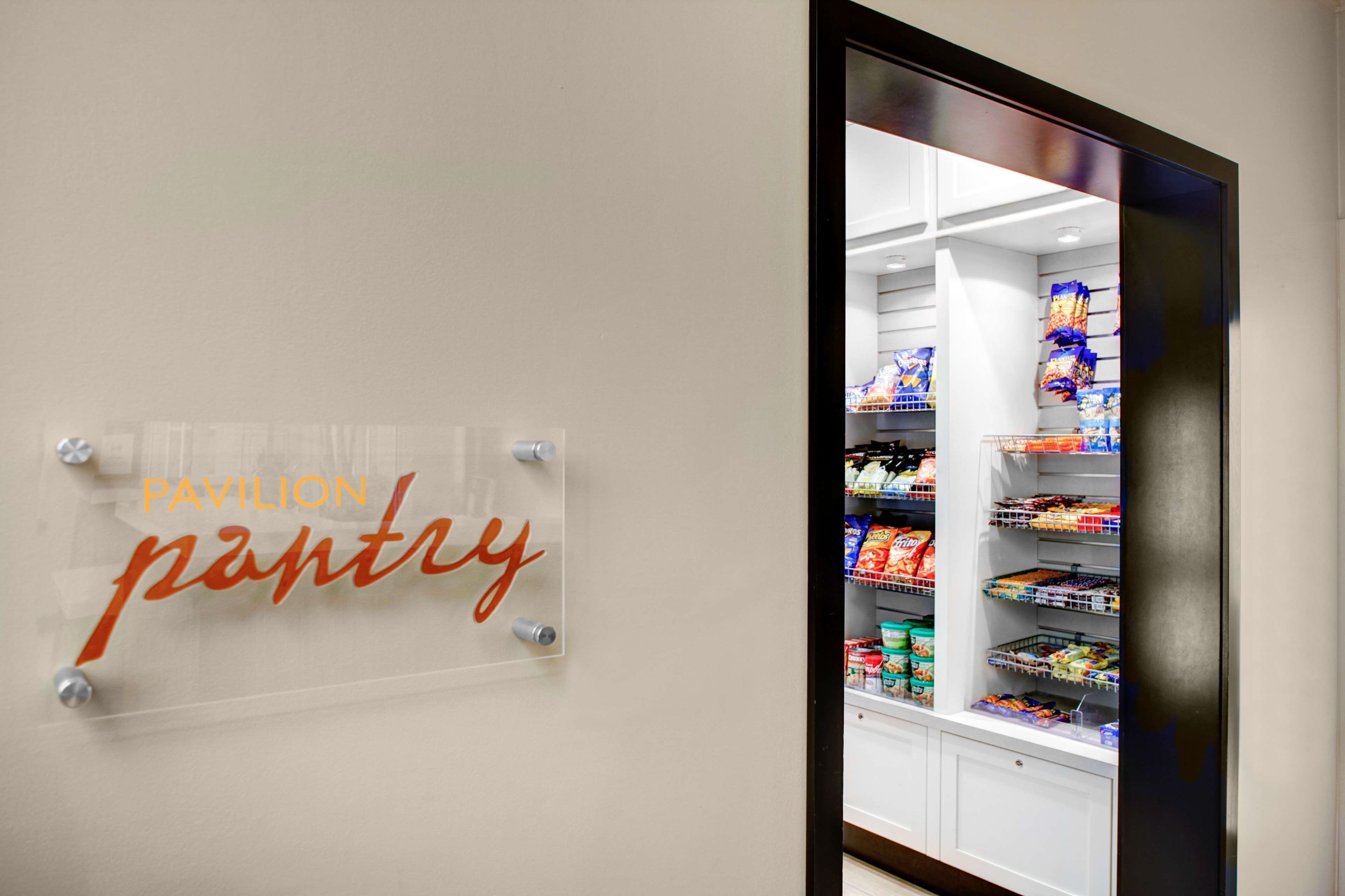 A clear sign reading "Pavilion Pantry" with a refrigerated display case in the background.