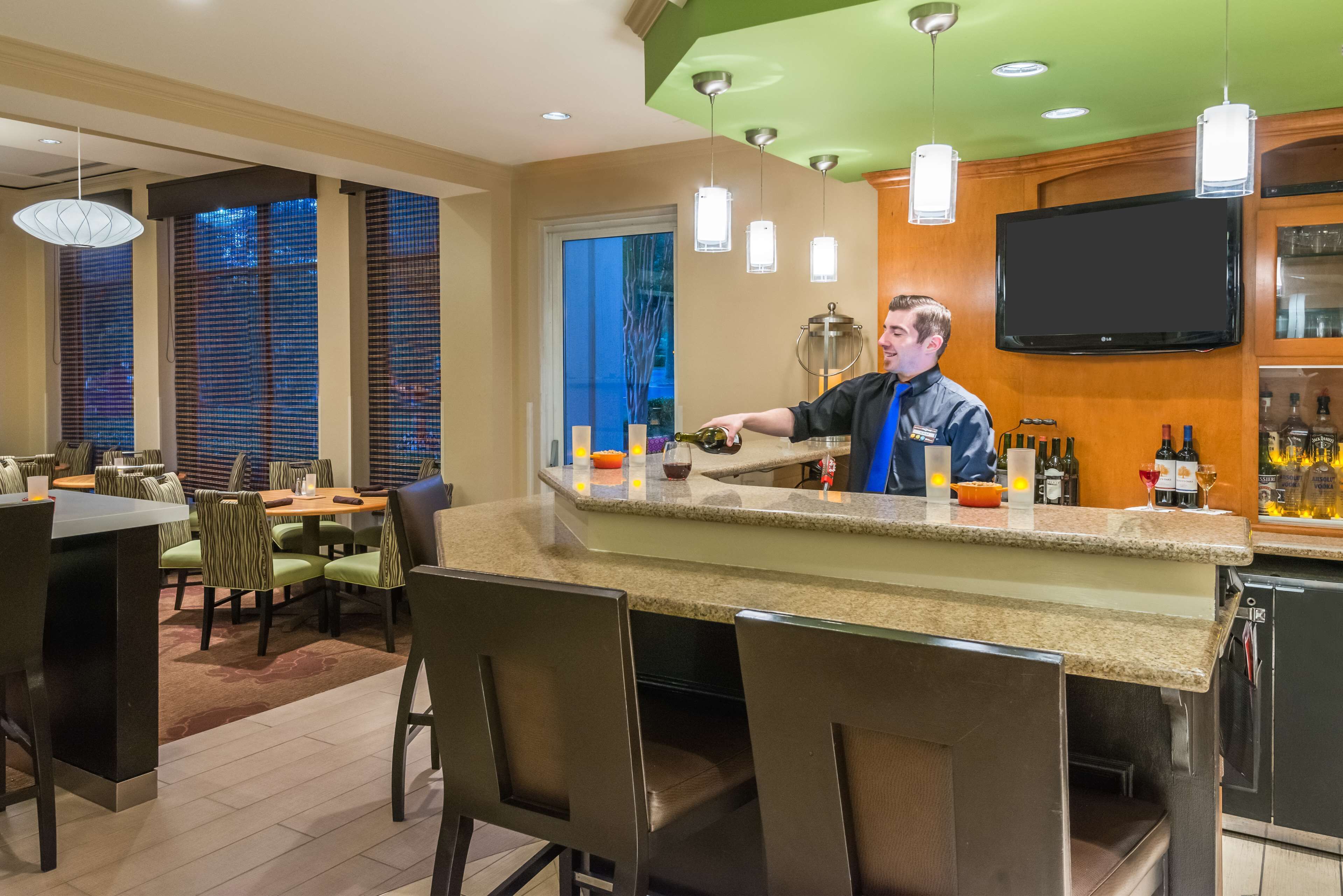 A bar area with a counter, bar stools, and a television mounted on the wall.