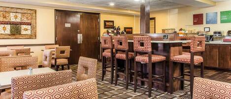 A restaurant with patterned booths and high stools, a bar area, and a tiled floor.