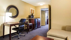 Une chambre d’hôtel équipée d’un bureau, de deux chaises, d’un canapé, d’un four à micro-ondes et d’un réfrigérateur.
