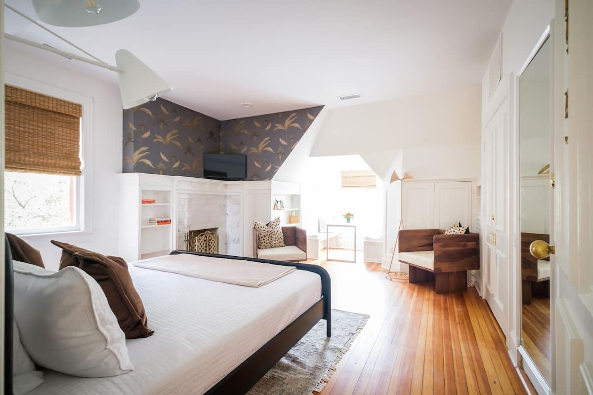 A bedroom with a bed, a TV, a desk, and a chair.