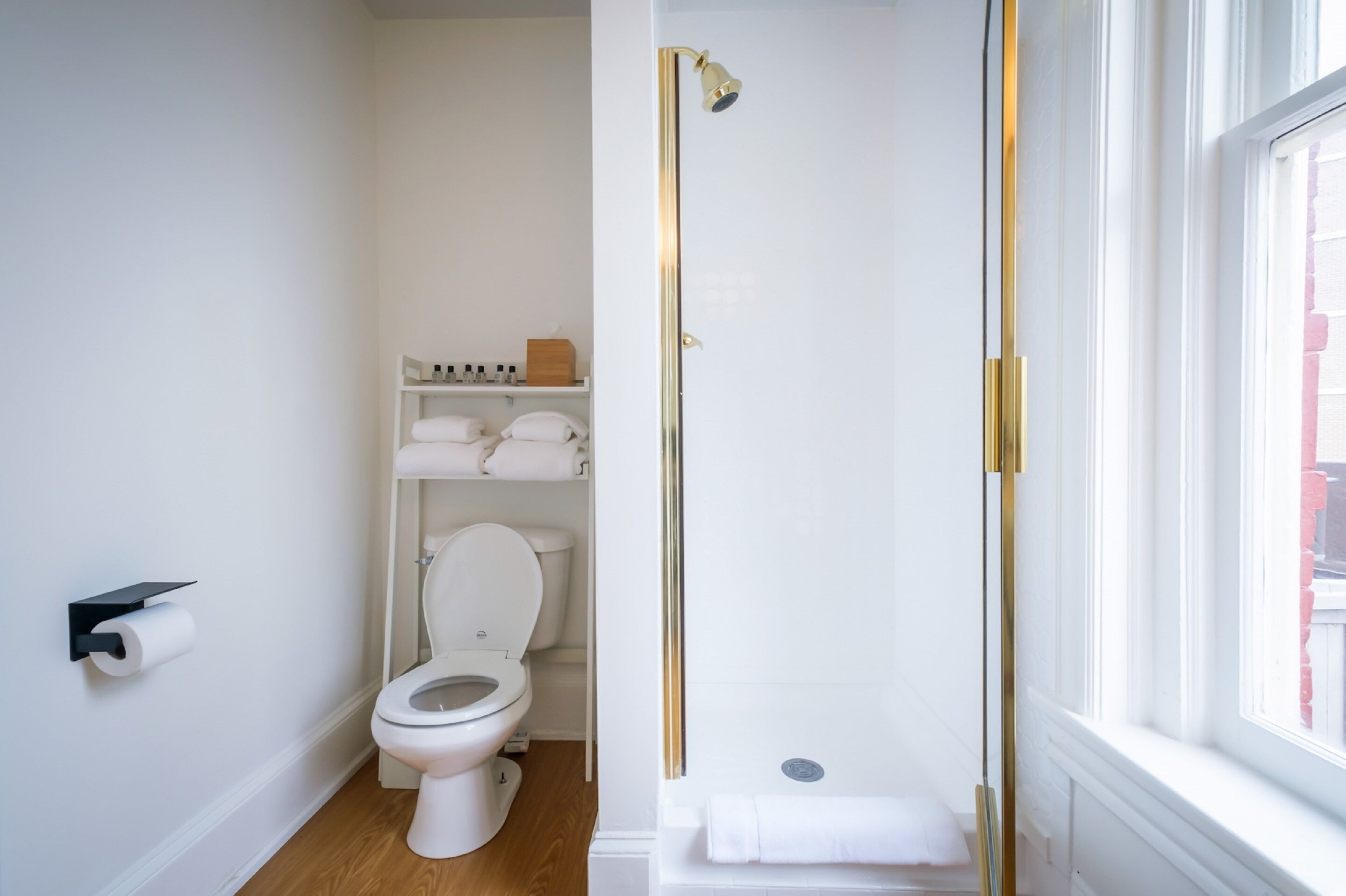 A modern bathroom with a toilet, a shower, and a window.