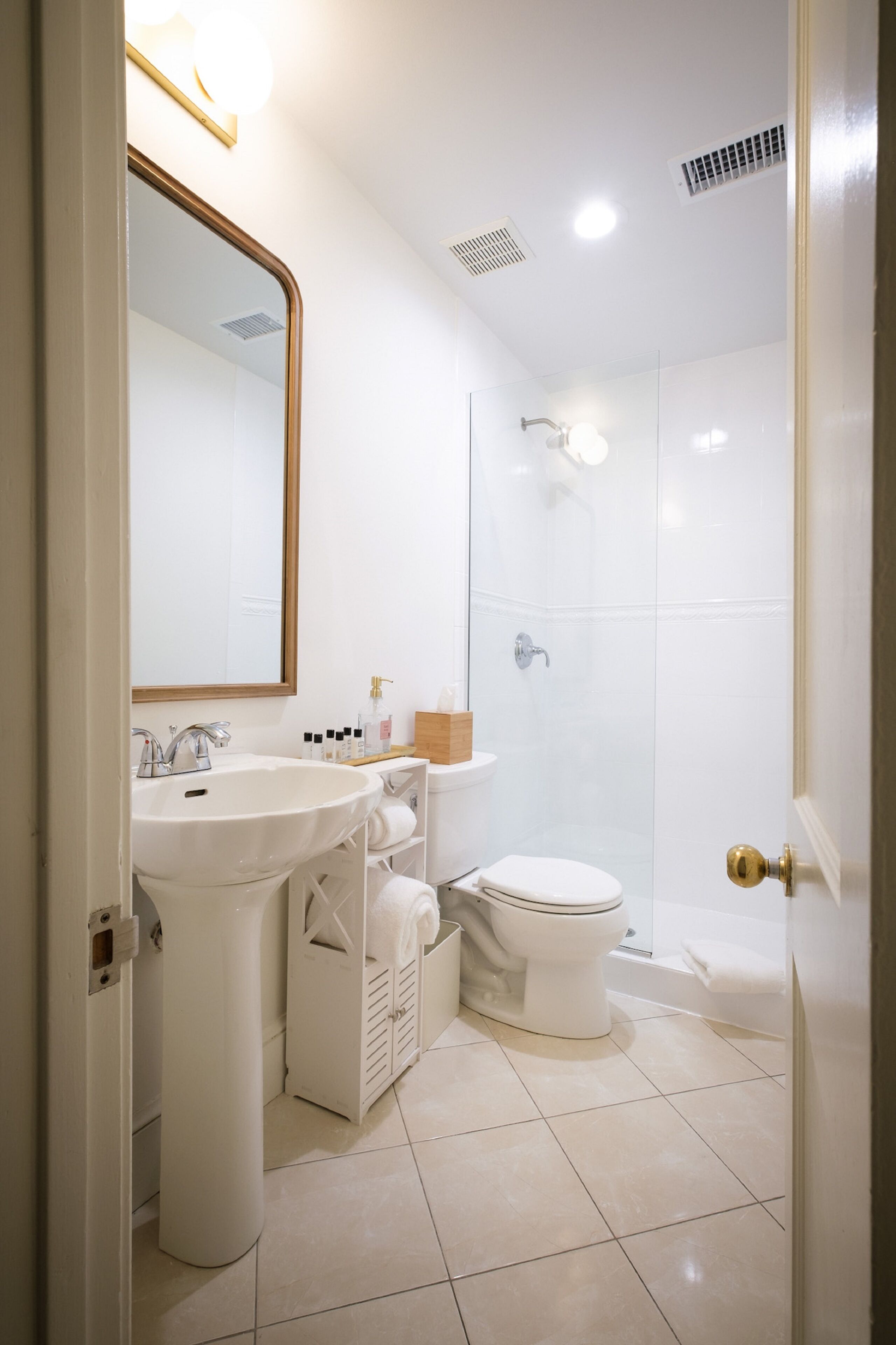 A modern bathroom with a sink, mirror, toilet, and shower.