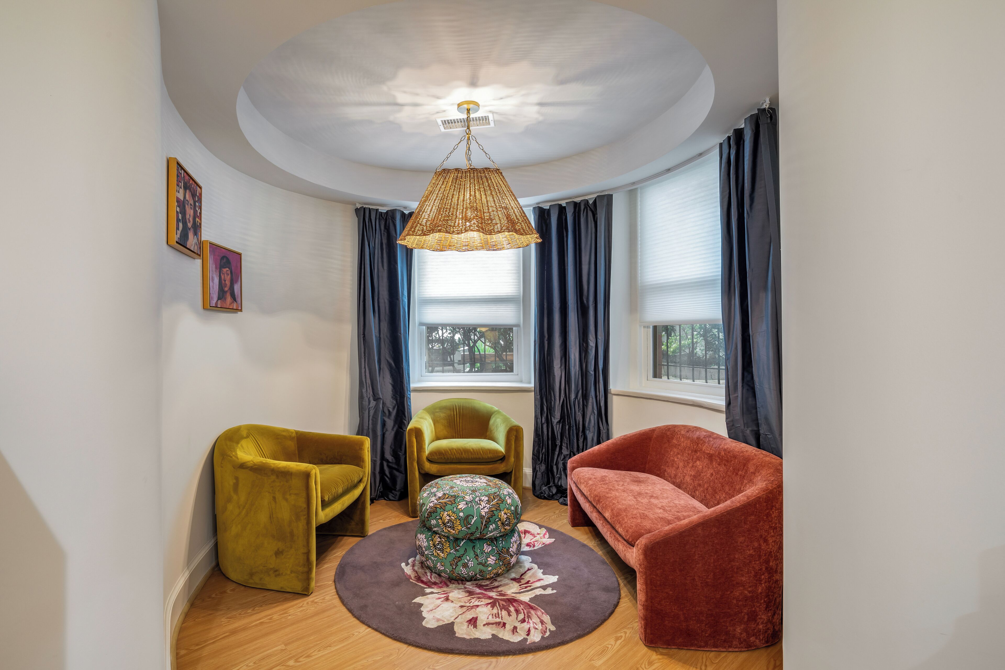 Uma sala de estar moderna com um tapete redondo, um candeeiro pendente e duas poltronas.
