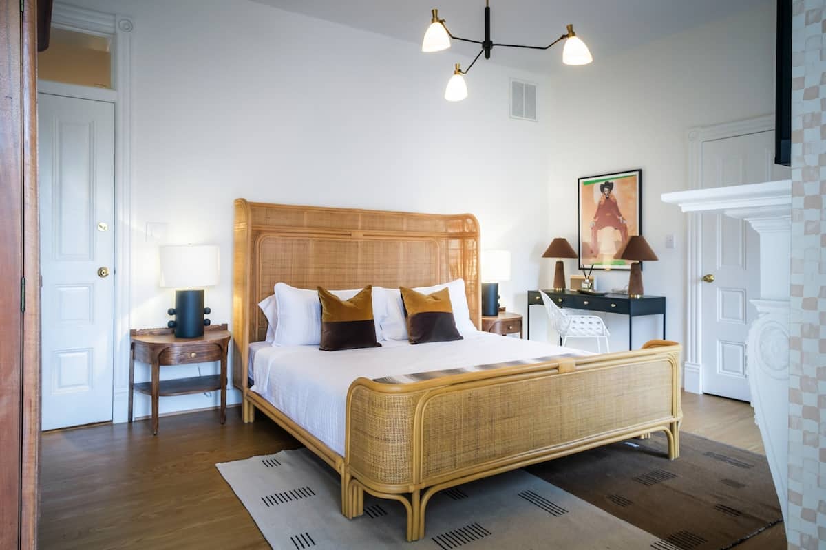 A bedroom with a large bed, bedside tables, a lamp, and a painting on the wall.