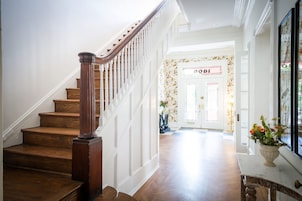 Una escalera de madera con barandillas blancas que lleva a una puerta con el número 8081.