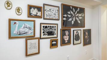 Eine Bilderwand mit verschiedenen gerahmten Kunstwerken, darunter florale und abstrakte Motive.