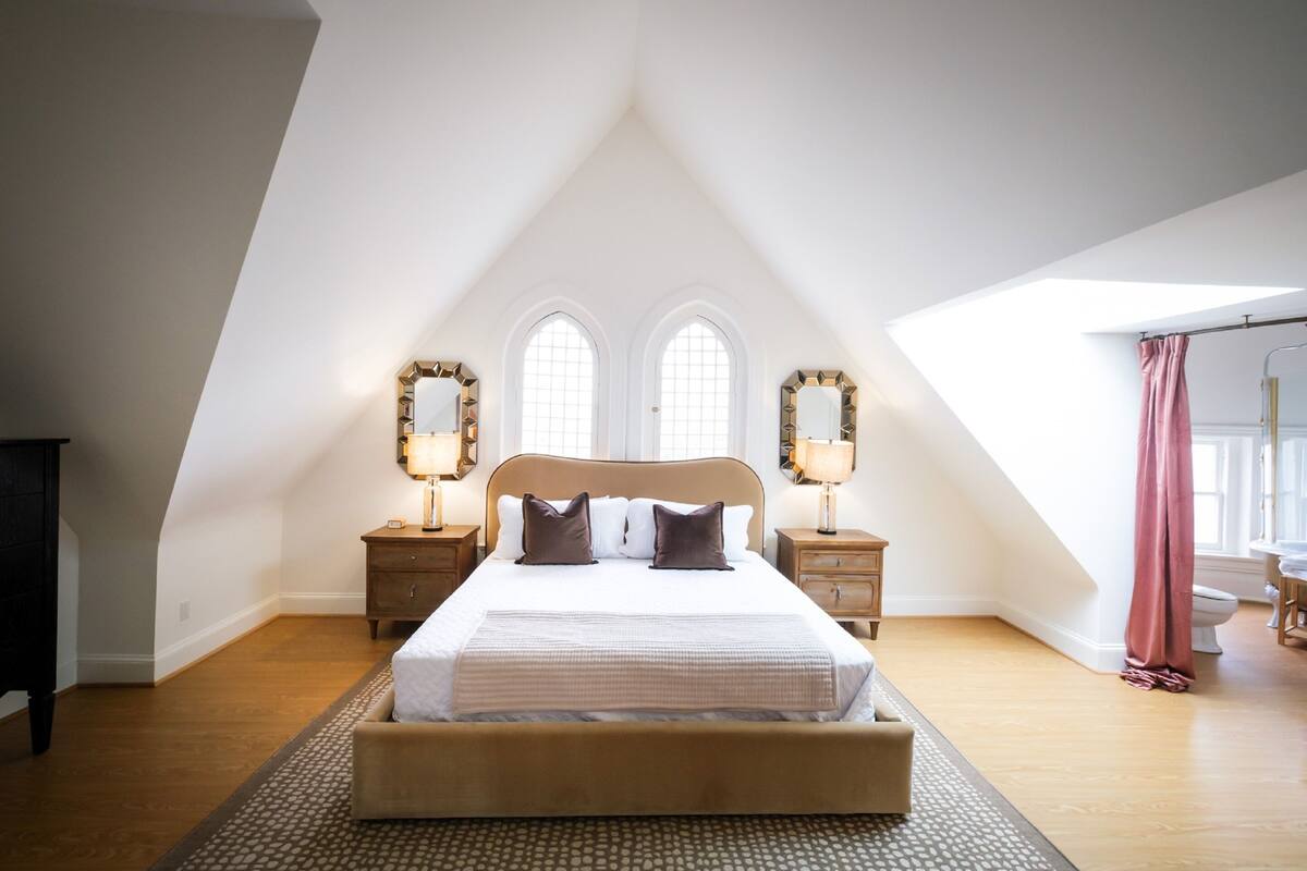 A bedroom with a large bed, two bedside tables, and a skylight.