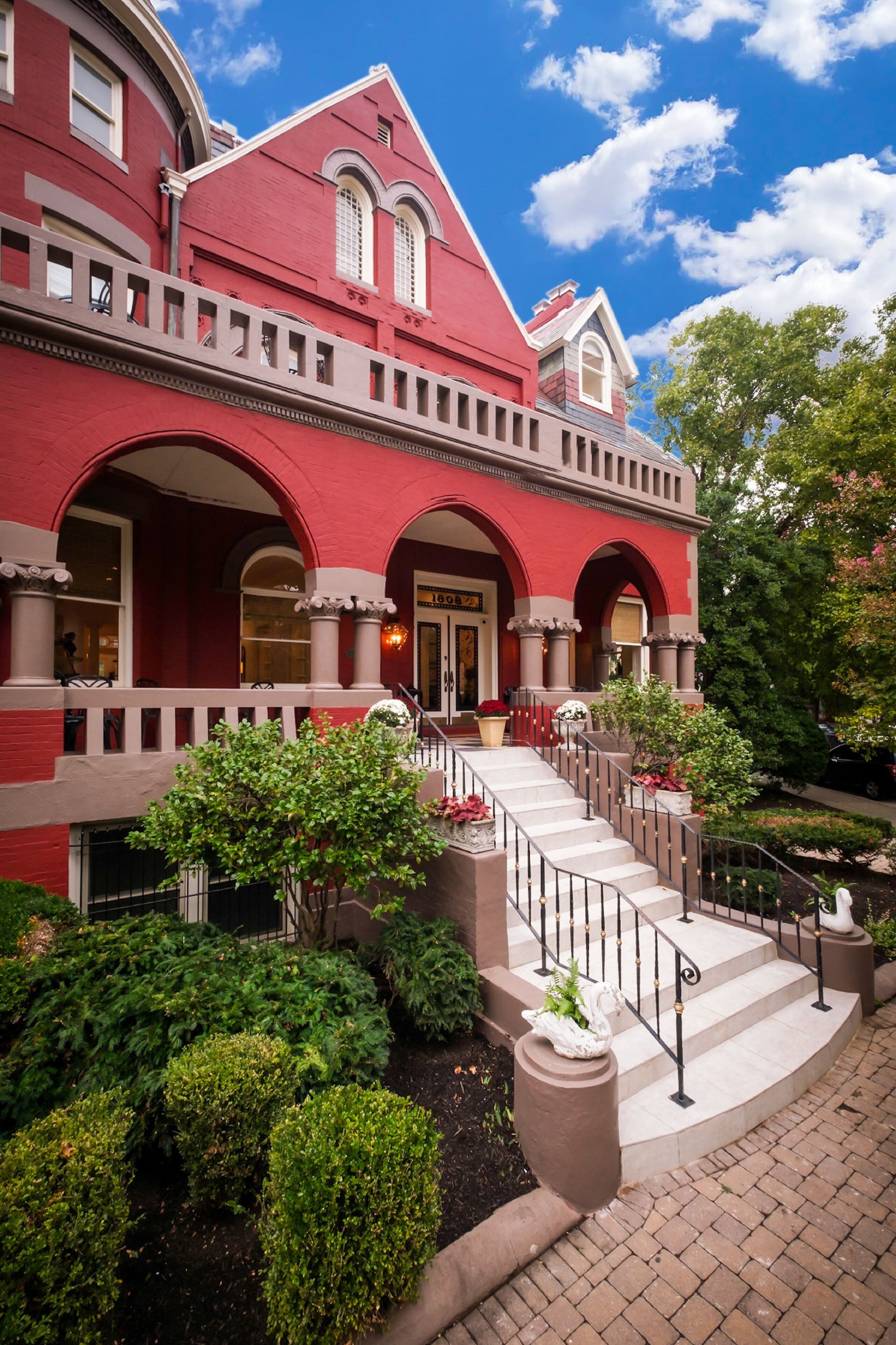 A red brick building with a grand entrance, a staircase, and well-maintained landscaping.