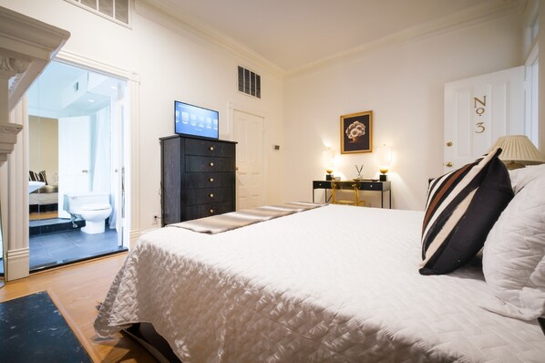 Un dormitorio con una cama grande, un aparador, un televisor y una puerta con el número 3.