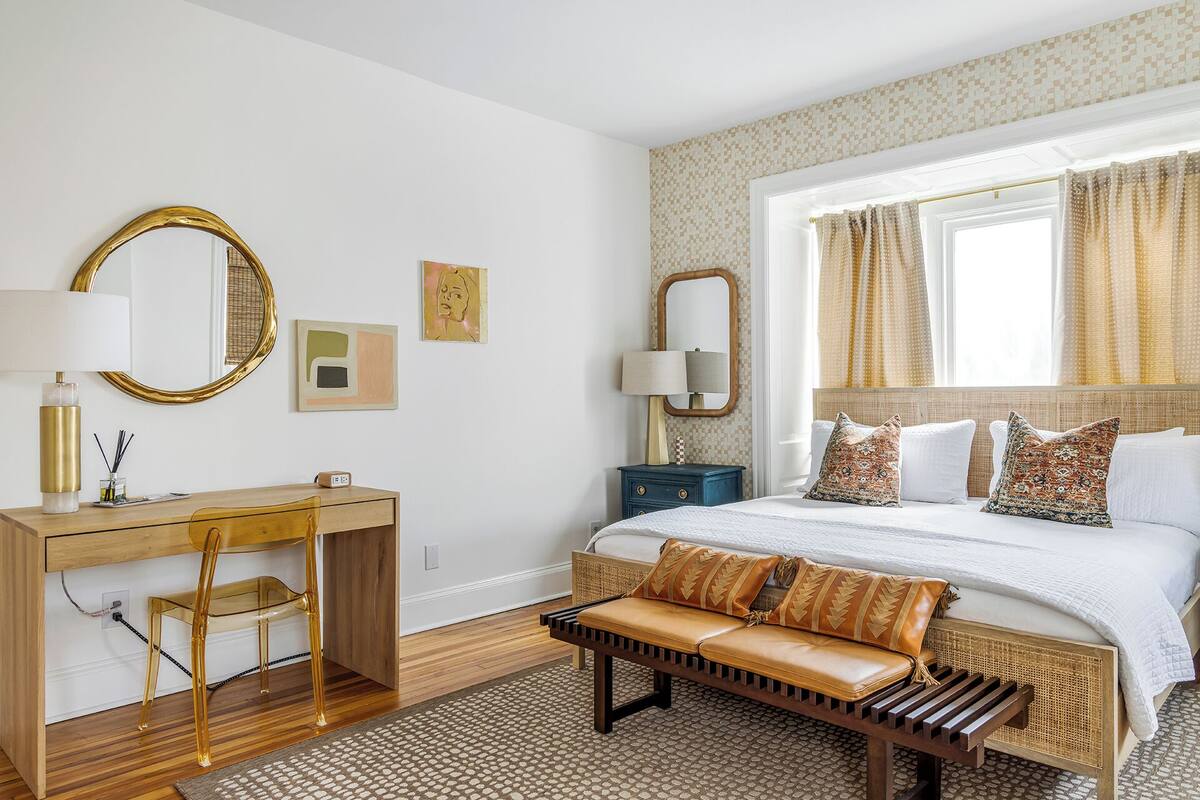 A bedroom with a bed, a desk, a chair, a bench, and a dresser.