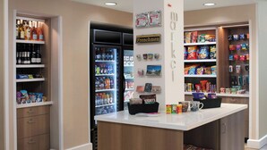 Un magasin bien organisé, avec des étagères remplies d’en-cas, un réfrigérateur et un comptoir où est exposée une machine à café.