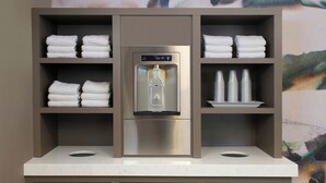 Une cuisine équipée d’un distributeur d’eau intégré, d’un réfrigérateur en acier inoxydable et d’étagères où sont pliées des serviettes.