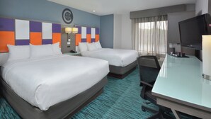 Une chambre d’hôtel avec deux lits, un bureau, une télévision et une horloge au mur.