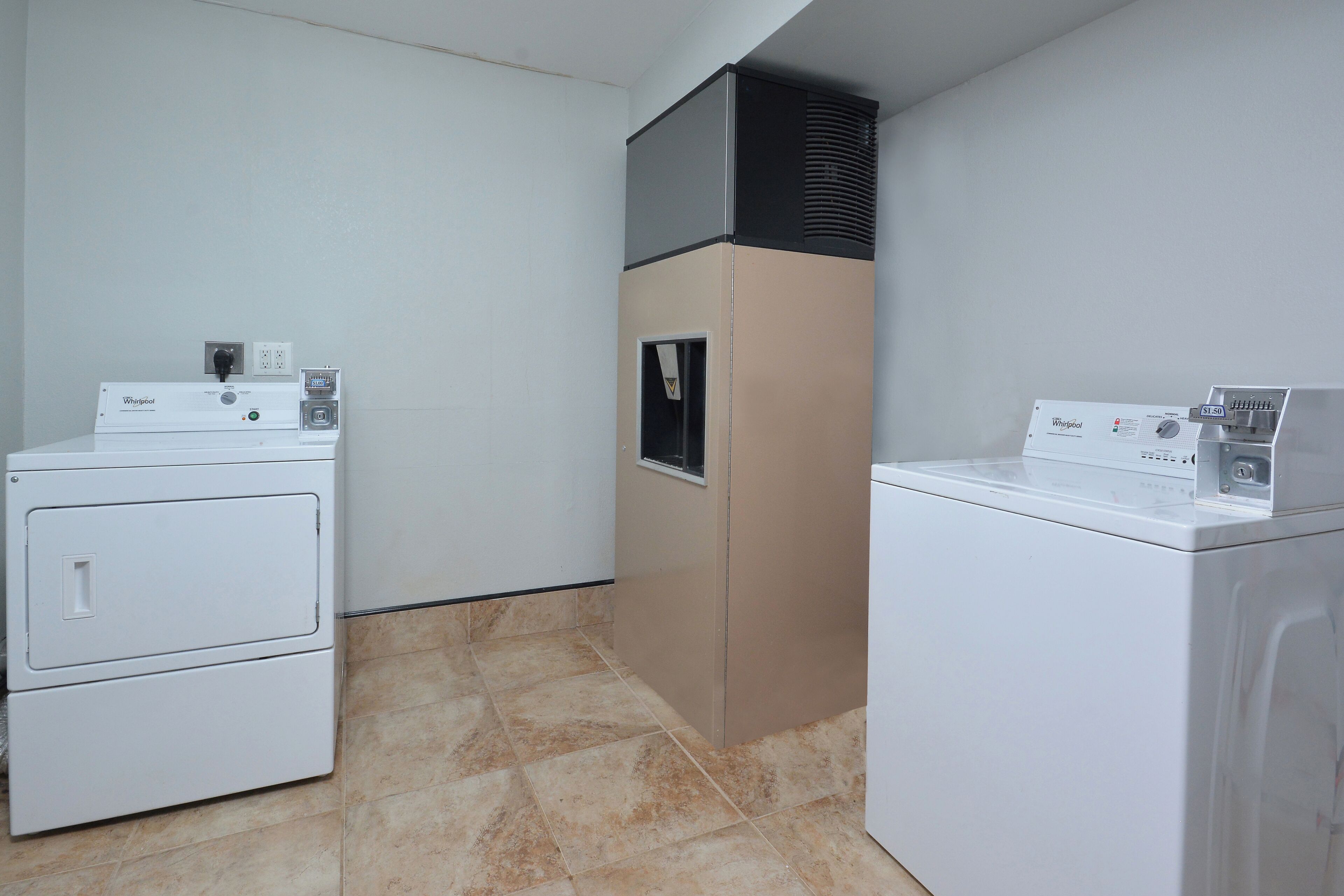 A laundry room with two stacked washers and a dryer, a vent hood, and a control panel.
